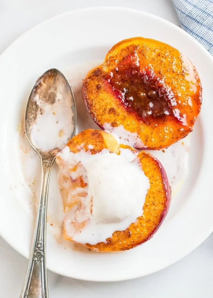 Delicious baked peaches served with a sprinkle of cinnamon and vanilla ice cream