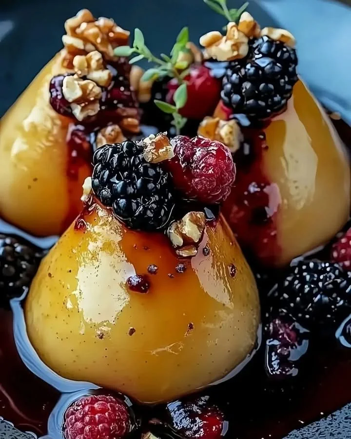 Baked pears topped with berries, honey, walnuts, and blue cheese on a plate