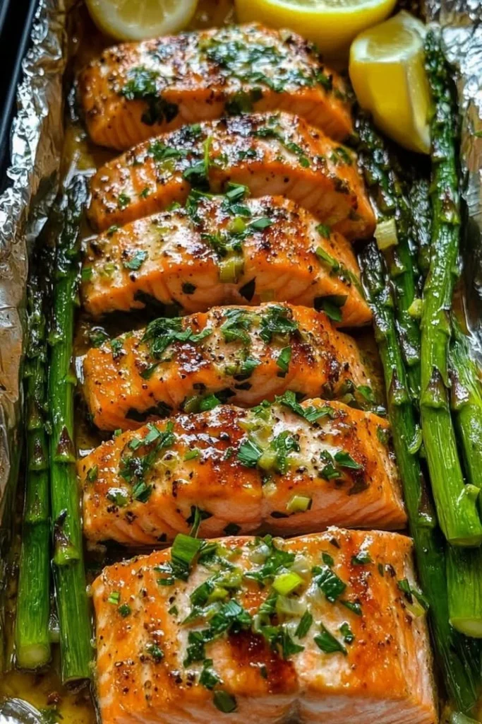 Baked salmon in foil with asparagus and lemon garlic butter sauce on a plate