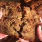 Loaf of moist homemade banana bread sliced on a wooden board