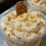 Slice of banana pudding cheesecake topped with whipped cream and banana slices.