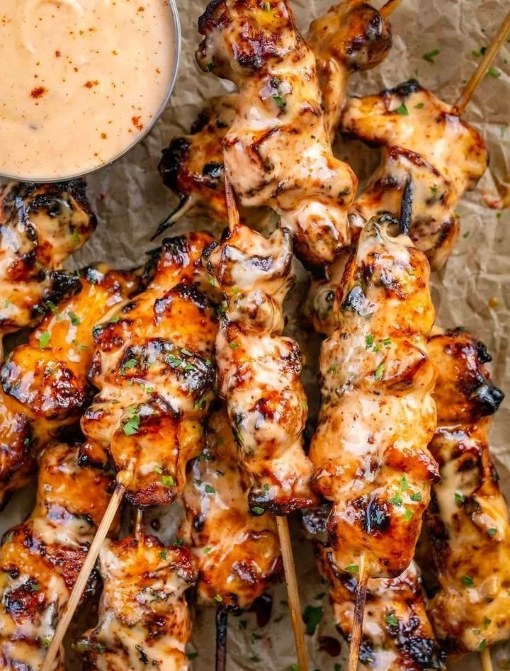 Spicy Bang Bang Chicken Skewers served with dipping sauce on a platter.