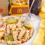 A bowl of Big Mac Pasta Salad with fresh ingredients and dressing.