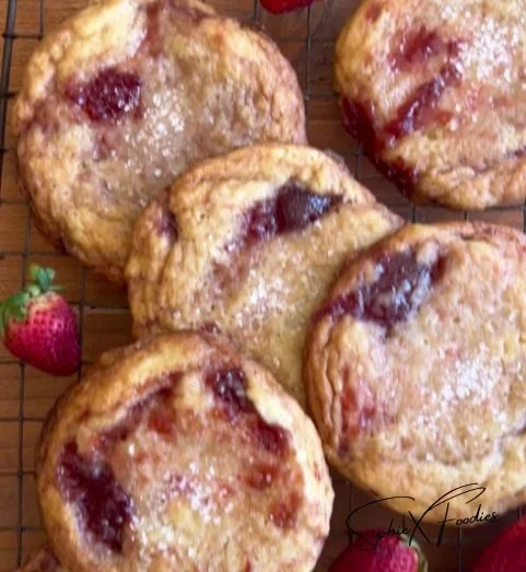 Buttery sugar cookies with strawberry jam swirls on a white plate