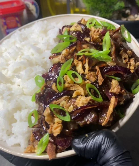 Plate of caramelized beef with onions garnished with herbs