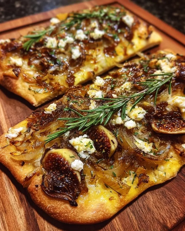 Caramelized onion and fig flatbread topped with rosemary on a wooden board