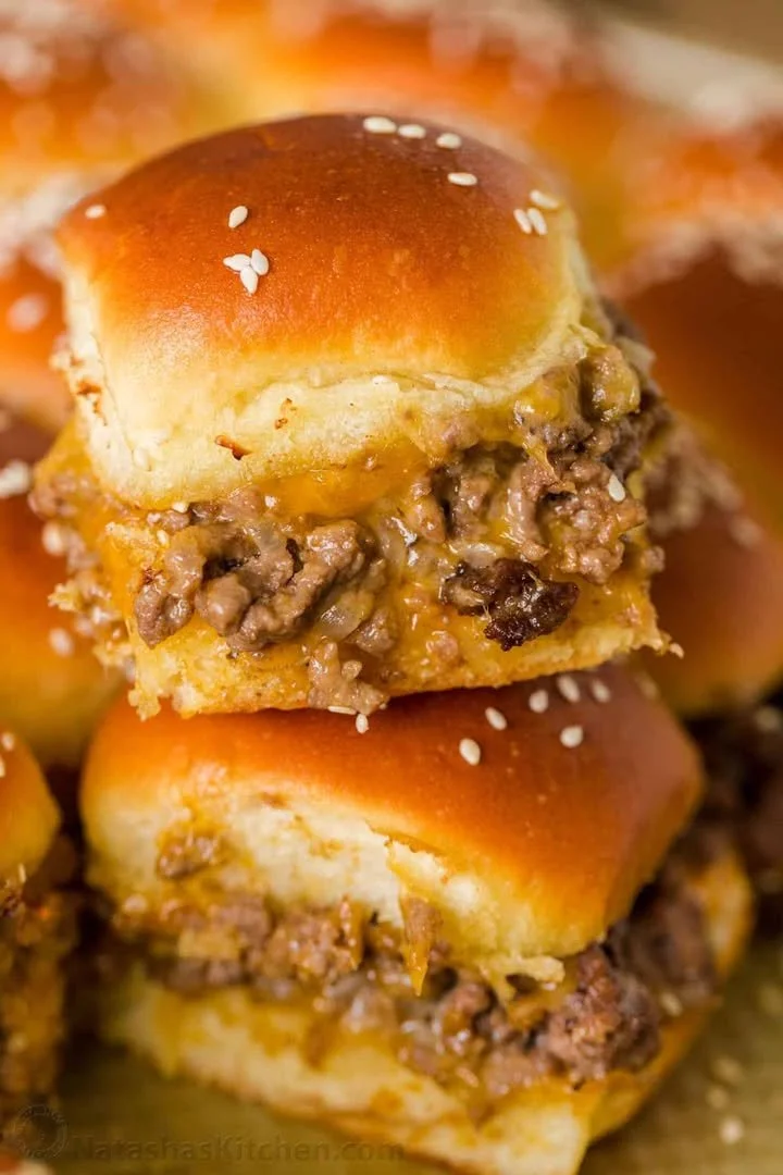 Delicious cheeseburger sliders served on a platter with toppings and sauces.