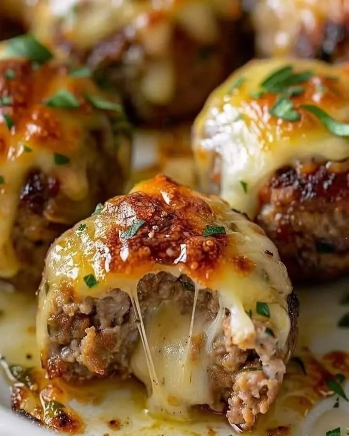Cheesy stuffed meatloaf bites served on a plate garnished with herbs