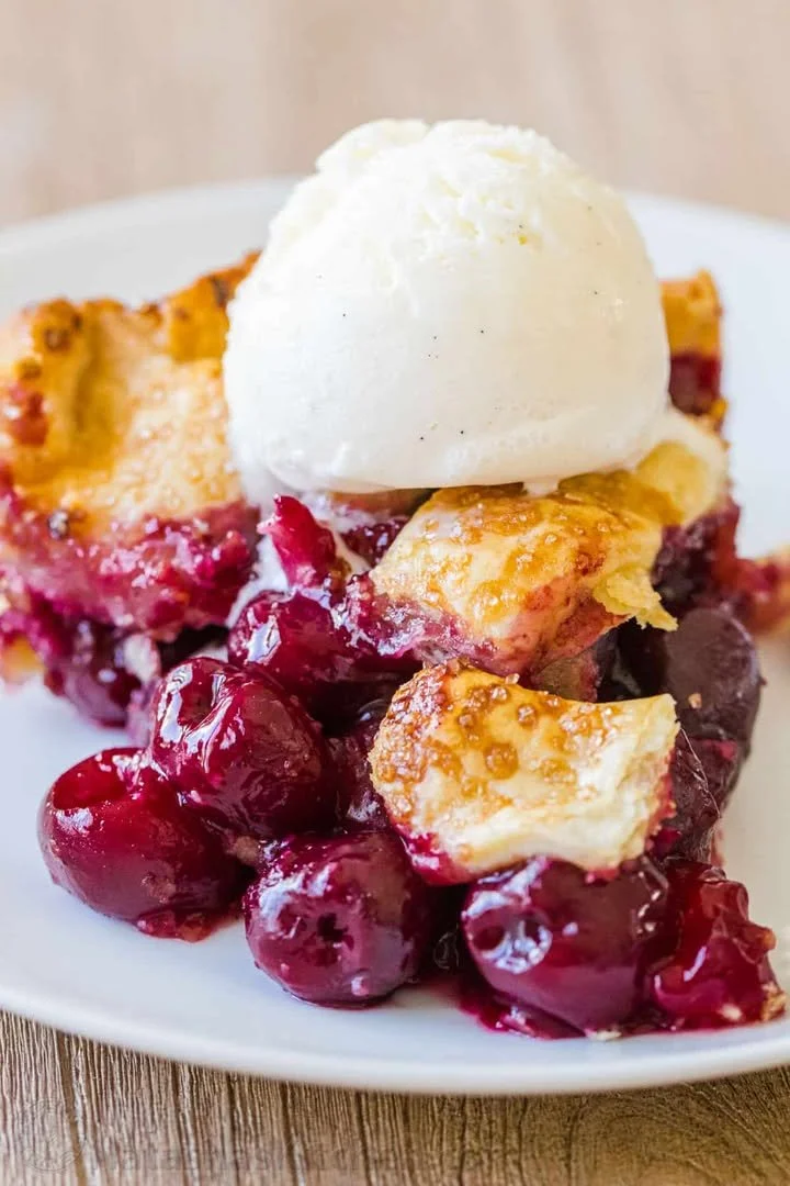 Delicious slice of homemade cherry pie served with a scoop of vanilla ice cream.