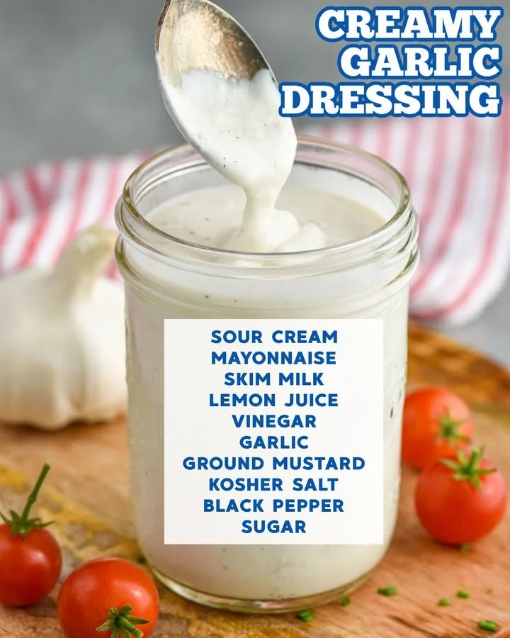 Creamy garlic dressing in a bowl with fresh herbs and garlic cloves
