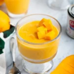 Creamy mango pudding served in a glass bowl with fresh mango slices on top