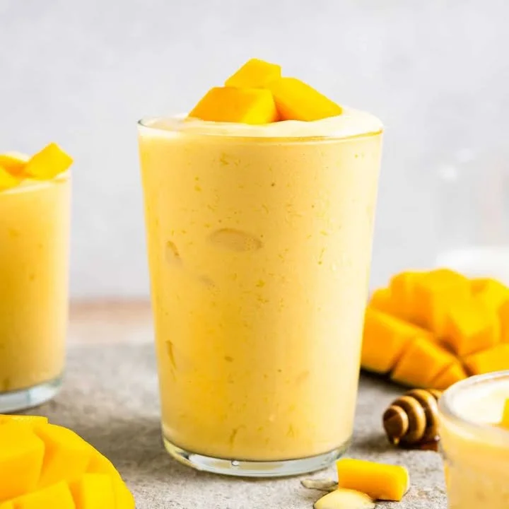 Creamy tropical mango smoothie in a glass garnished with fresh mango slices