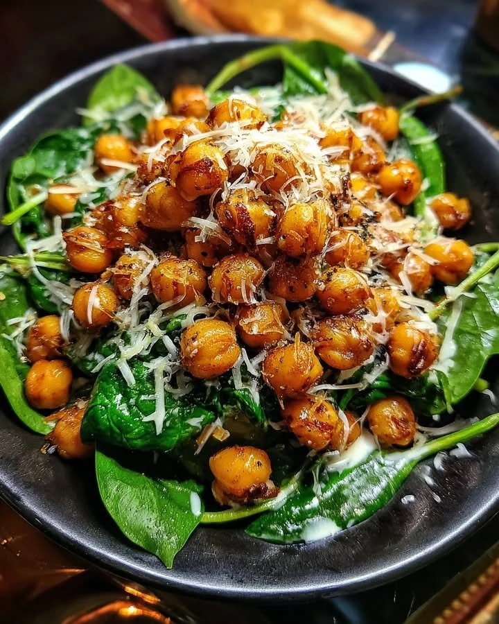 Plate of crispy cheddar chickpeas and spinach drizzled with lemon sauce.