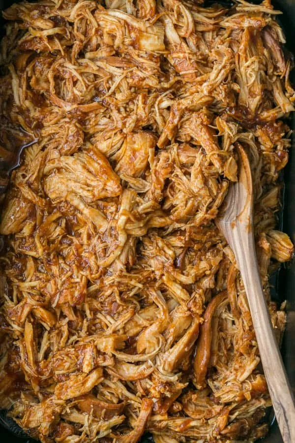 Crockpot Pulled Chicken dish served in a bowl with herbs and spices.
