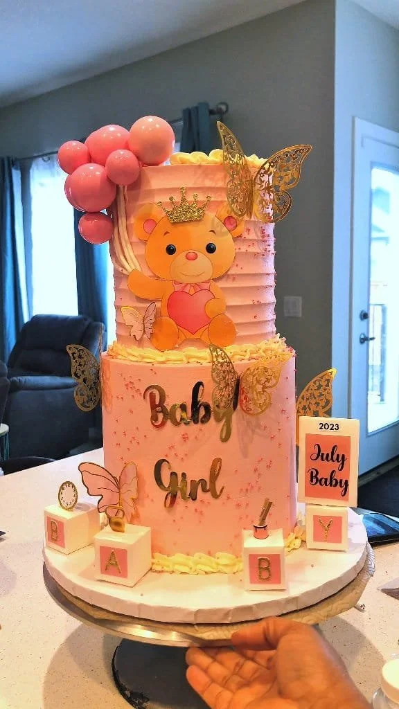 Elegant pink baby shower cake decorated with delicate flowers and a 'Welcome Baby' message.