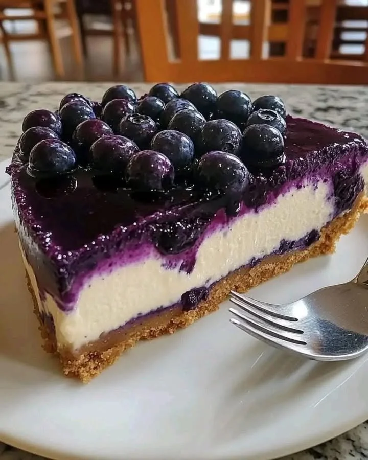 Slice of fresh blueberry cheesecake topped with blueberries and whipped cream