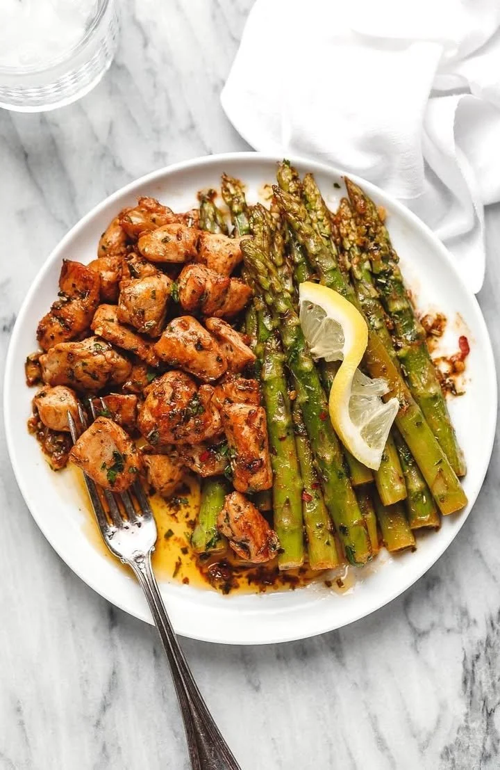 Garlic Butter Chicken Bites served with asparagus on a plate