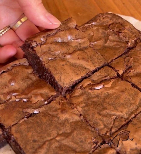 Delicious gluten free brownies on a wooden plate with chocolate drizzle