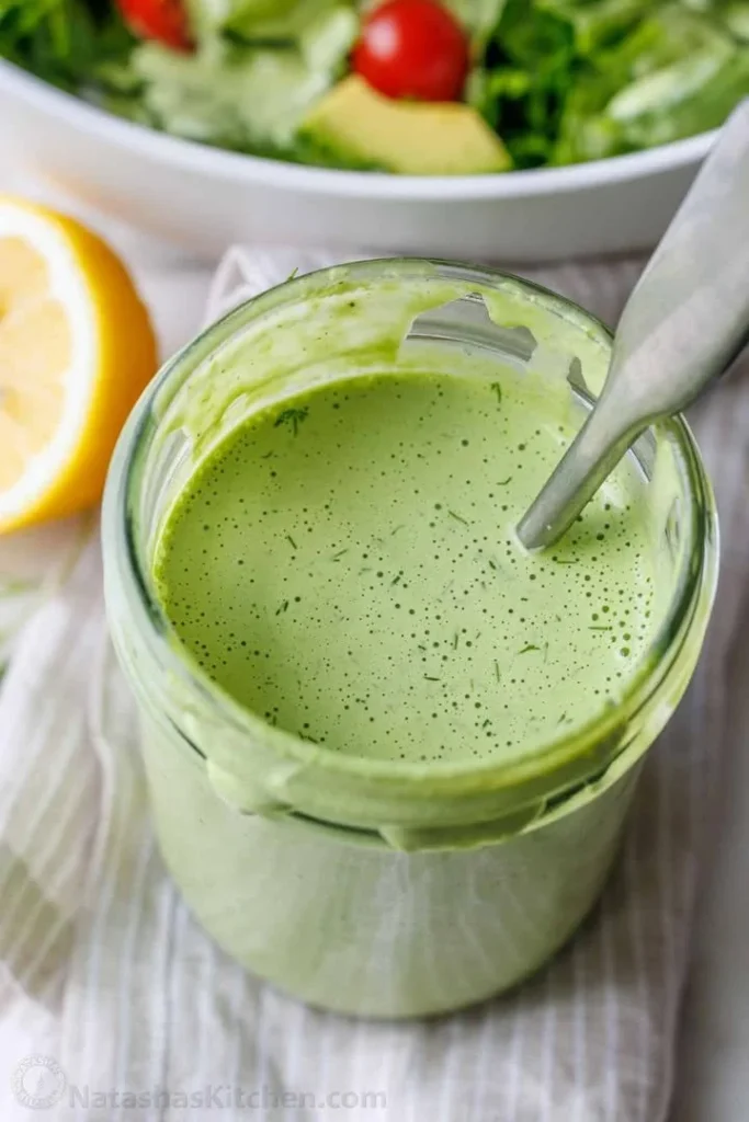 Homemade Green Goddess Dressing in a glass jar with fresh herbs