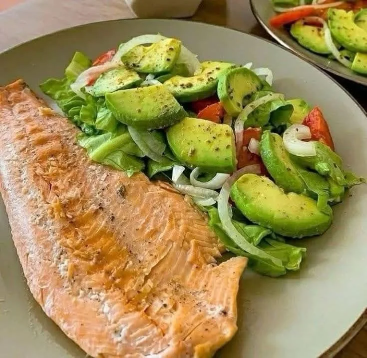 Grilled salmon fillet served with a colorful avocado salad.