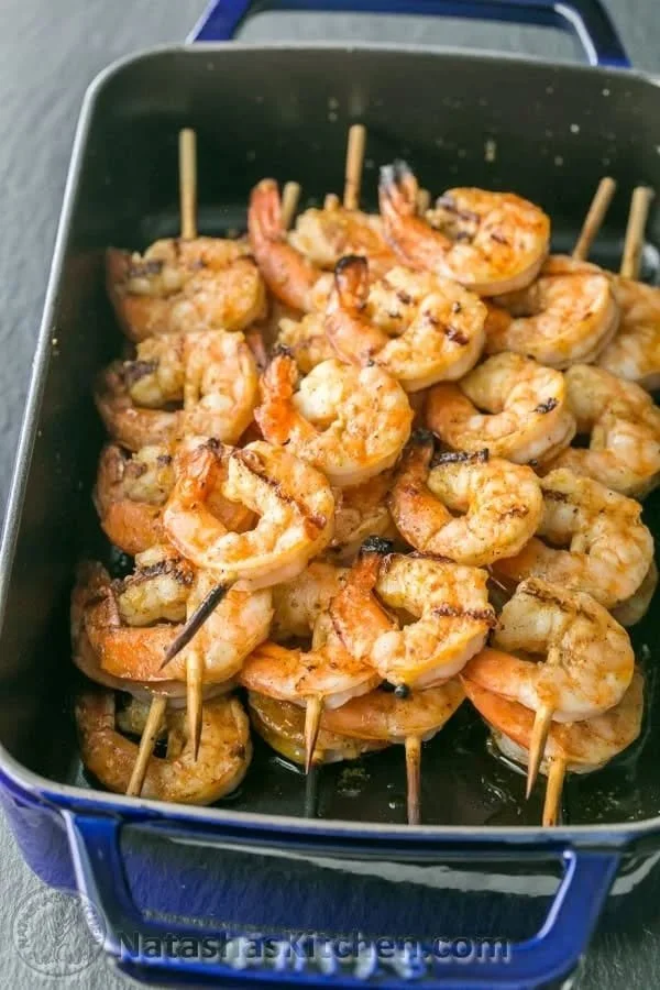 Delicious grilled shrimp skewers on a platter with fresh lemon and herbs