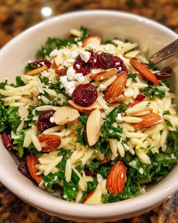 A vibrant Kale and Orzo Salad with cranberries and almonds presented in a bowl.