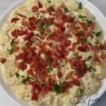 Delicious loaded potato salad topped with bacon, cheese, and chives.