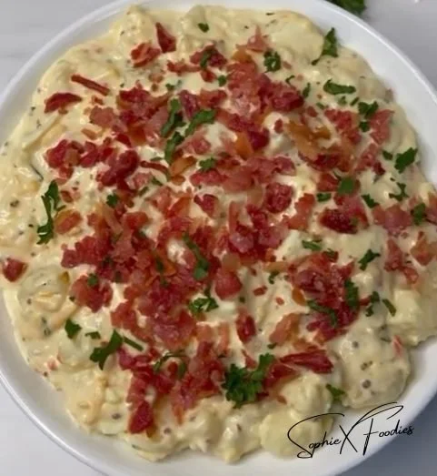 Delicious loaded potato salad topped with bacon, cheese, and chives.