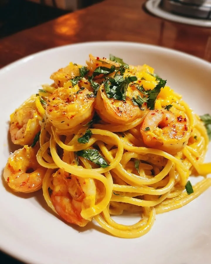 Delicious bowl of Mango Coconut Pasta with Chili Lime Shrimp garnished with herbs