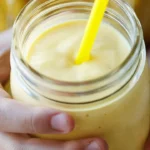 Delicious mango smoothie in a glass garnished with fresh mango slices