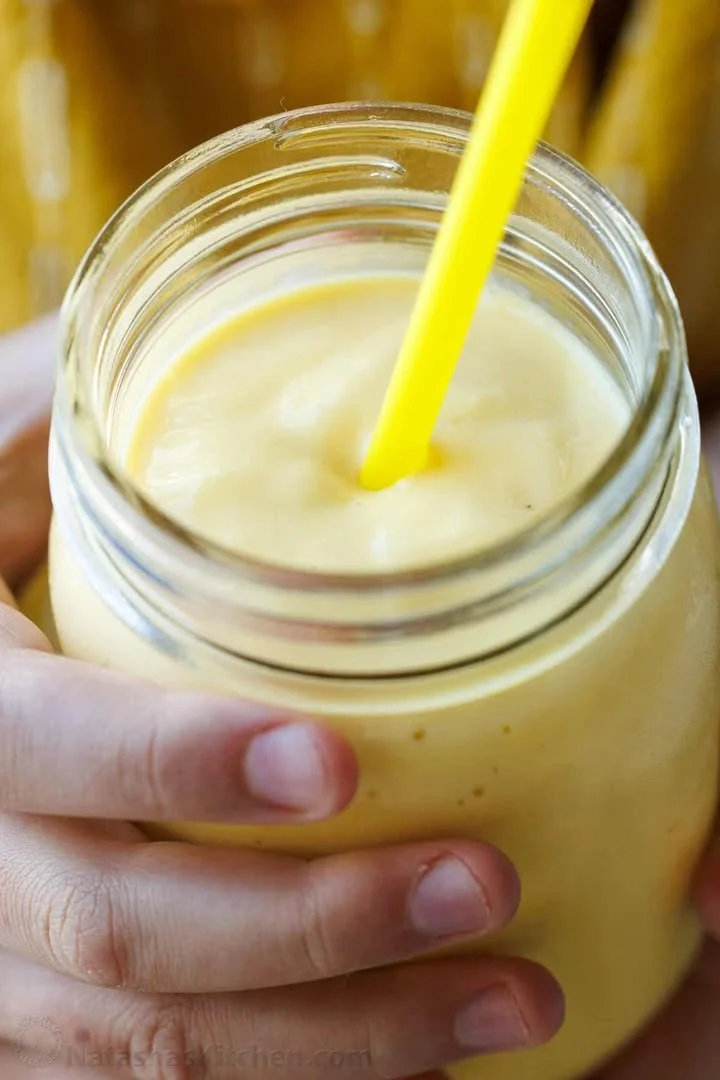 Delicious mango smoothie in a glass garnished with fresh mango slices