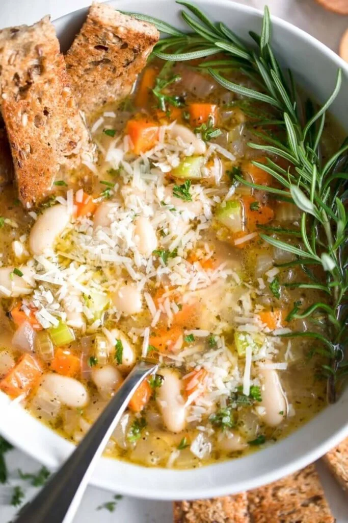 Bowl of Mediterranean white bean soup with fresh herbs and vegetables
