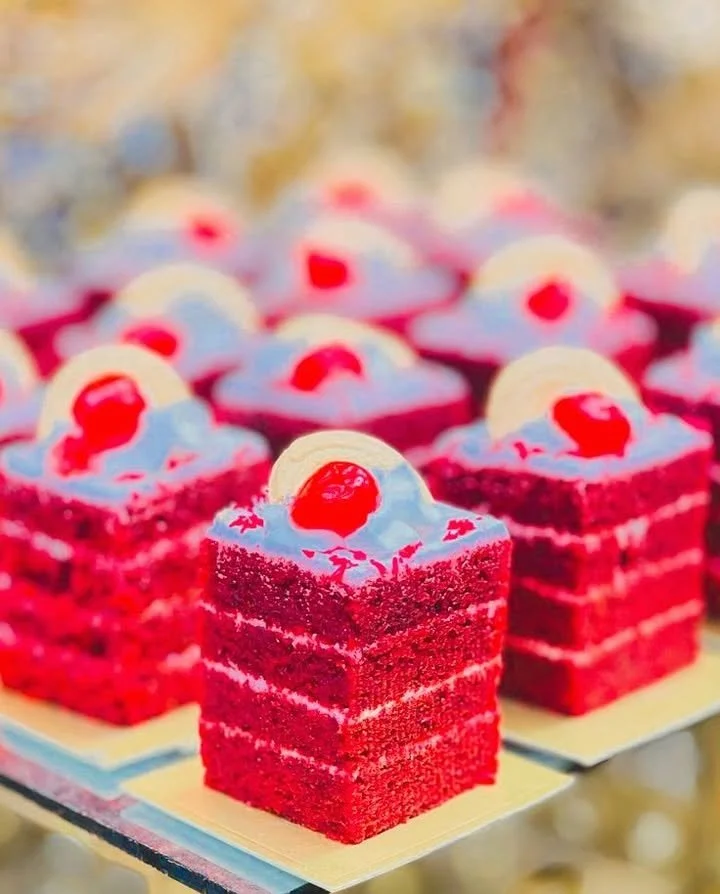 Mini red velvet layer cake squares on a white plate with cream cheese frosting