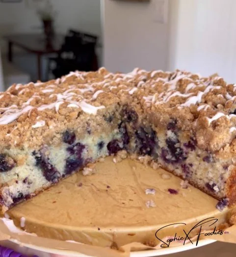 Moist sour cream cake topped with fresh blueberries on a white plate