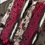 Slice of Oreo Red Velvet Cake topped with Oreo crumbs and cream cheese frosting