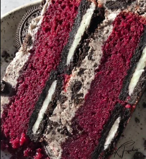 Slice of Oreo Red Velvet Cake topped with Oreo crumbs and cream cheese frosting