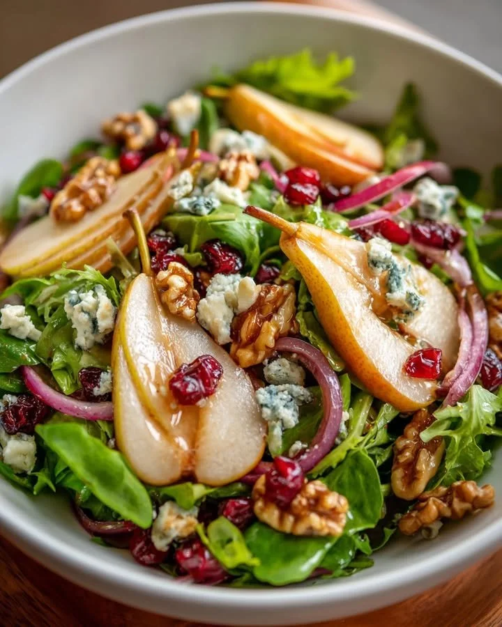 A refreshing pear, blue cheese, and walnut salad in a bowl with vibrant colors.
