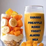 A delicious Pineapple Mango Smoothie in a glass with tropical fruits
