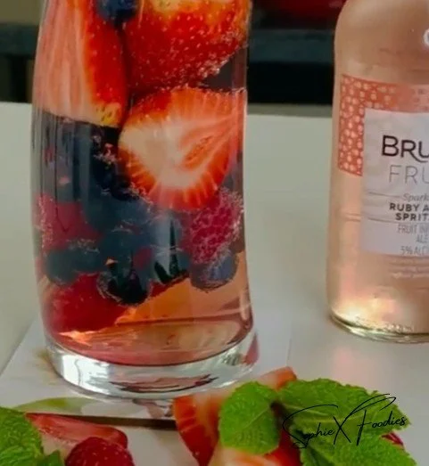 A delicious Pink Drink with strawberries and coconut milk served in a clear cup.