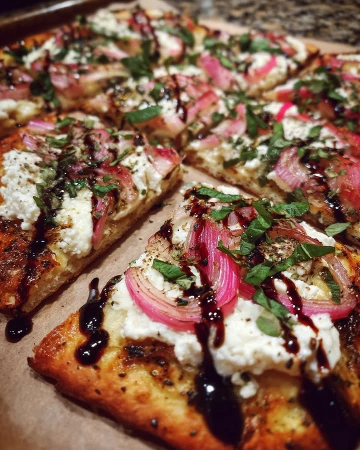 Rhubarb flatbread topped with balsamic and fresh herbs on a wooden board