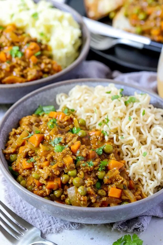 Plate of savoury mince with curry served with rice and garnished with herbs