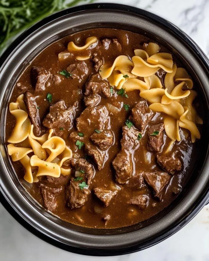 Delicious slow cooker beef and noodles in a bowl, showcasing tender beef and savory broth.