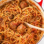 Plate of spaghetti meatballs garnished with fresh herbs and Parmesan cheese