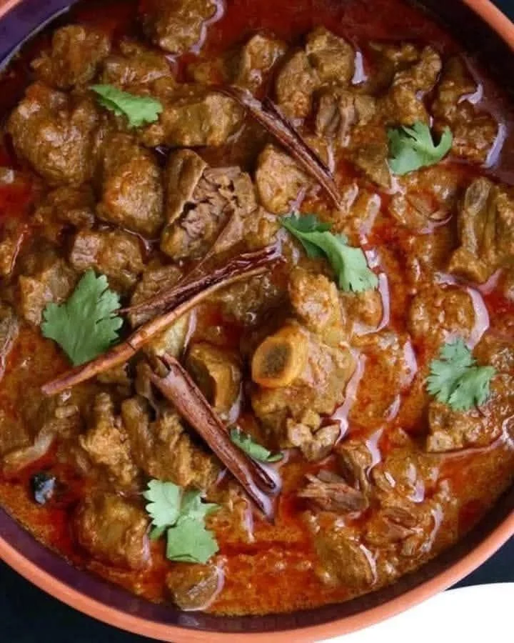 Delicious Spicy Mutton Curry served with rice and garnished with fresh herbs.