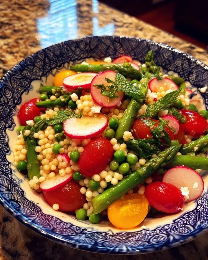 A colorful bowl of Spring Couscous Salad with fresh vegetables and herbs