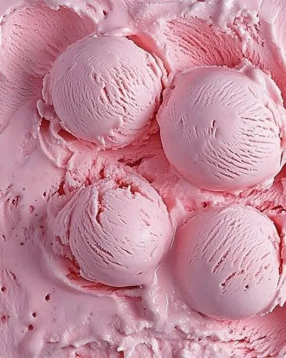 Homemade strawberry ice cream in a cone topping with fresh strawberries