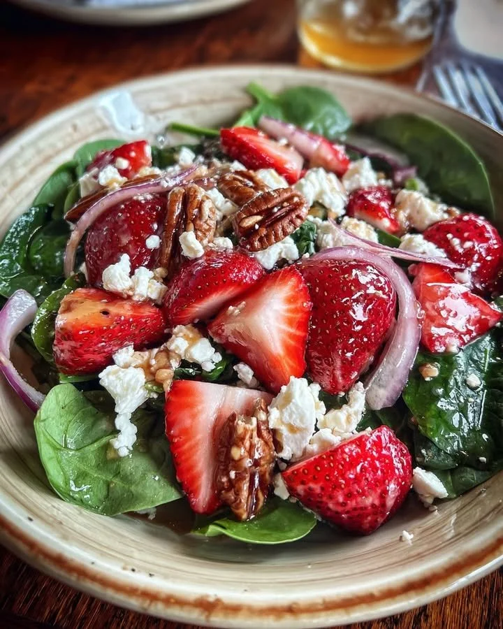 Strawberry spinach salad with goat cheese and pecans in a bowl