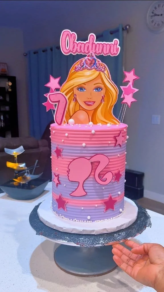 Stylish Barbie-themed cake decorated with pink accents and doll figurines.