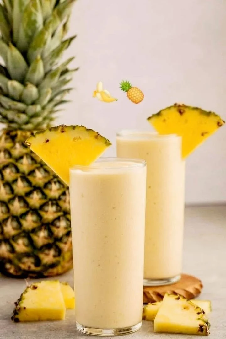 Refreshing summer pineapple banana smoothie in a glass with tropical fruits.