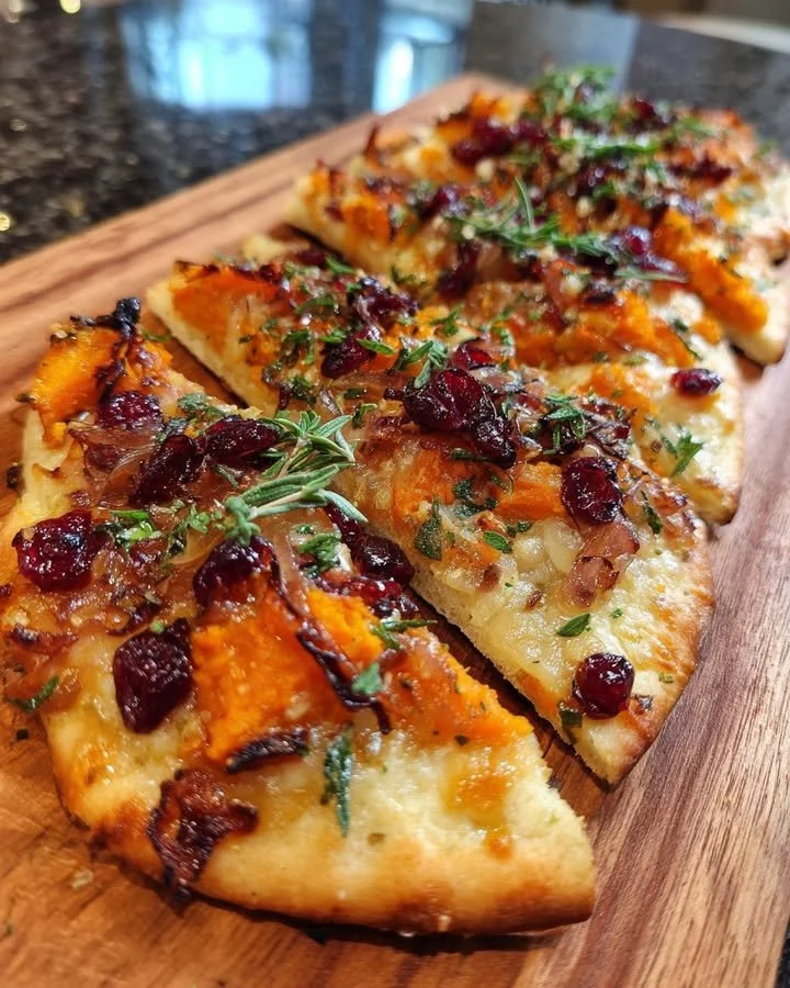 Sweet potato flatbread with sage, caramelized onions, and cranberry sauce on a plate.